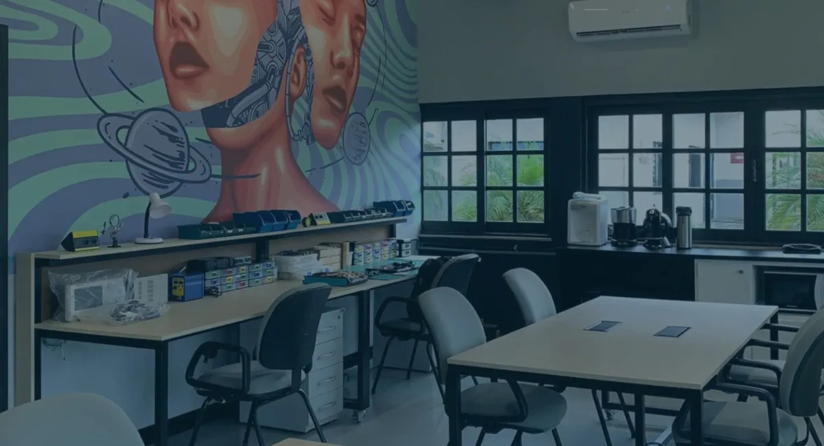 Sala do Fab Lab Joinville com bancadas de eletrônica, mesa de reuniões e um grande mural colorido na parede.