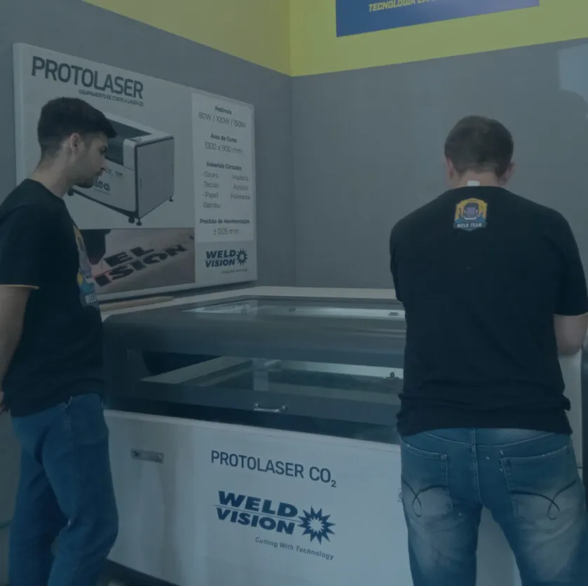 Duas pessoas operando a máquina de corte a laser Protolaser CO₂ no Fab Lab Joinville